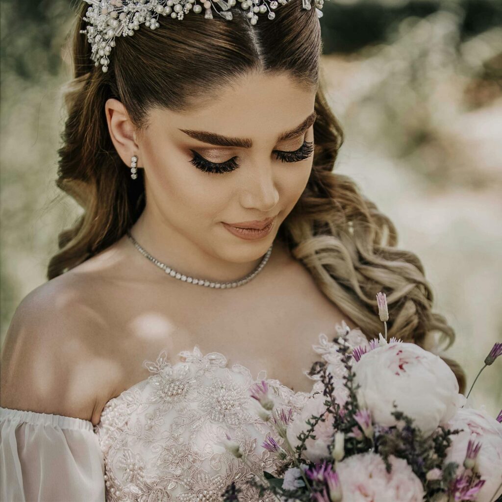 Beautiful bride in an elegant dress holding a flower bouquet, captured in a garden setting.