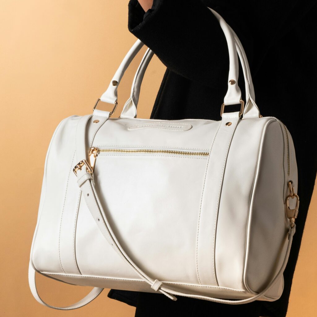 Chic white leather handbag with handle and strap, perfect for fashion and travel.