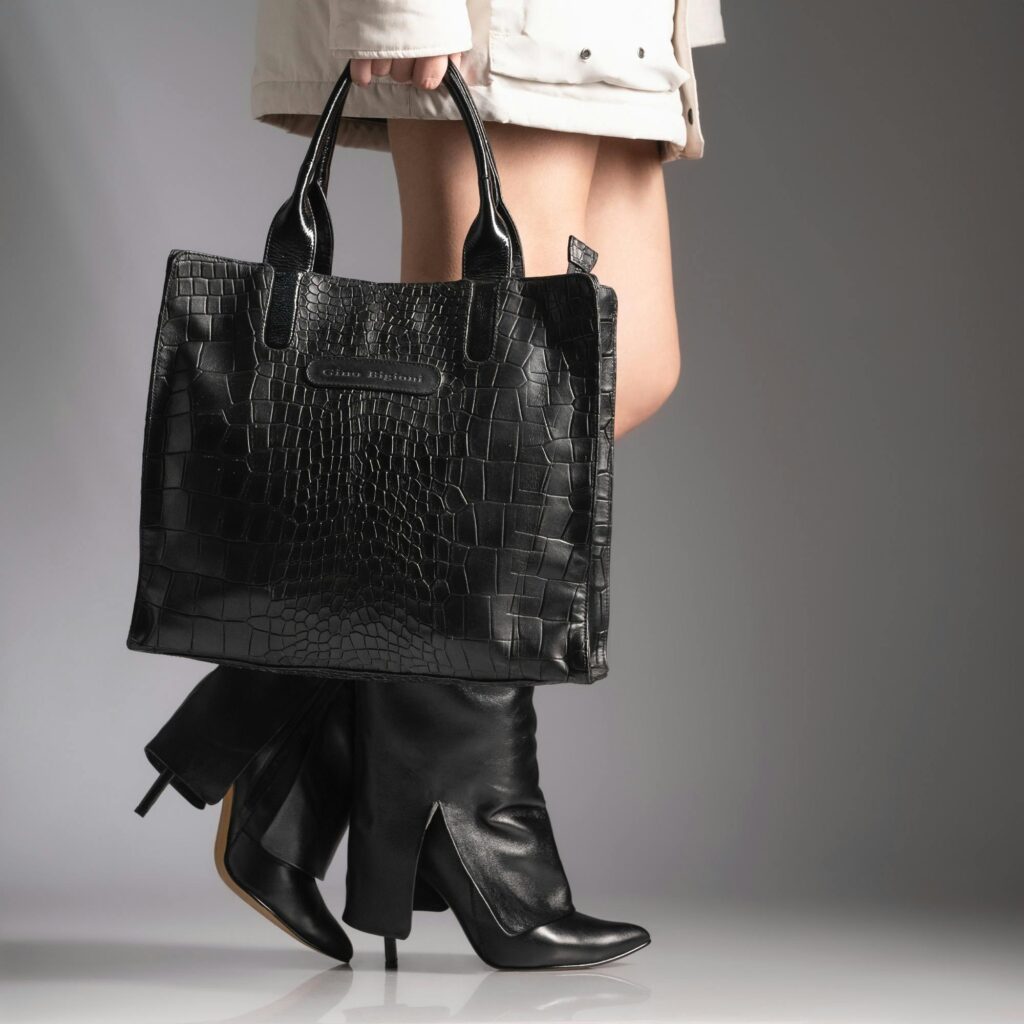 Stylish leather bag and high-heeled boots captured in a chic studio setting.
